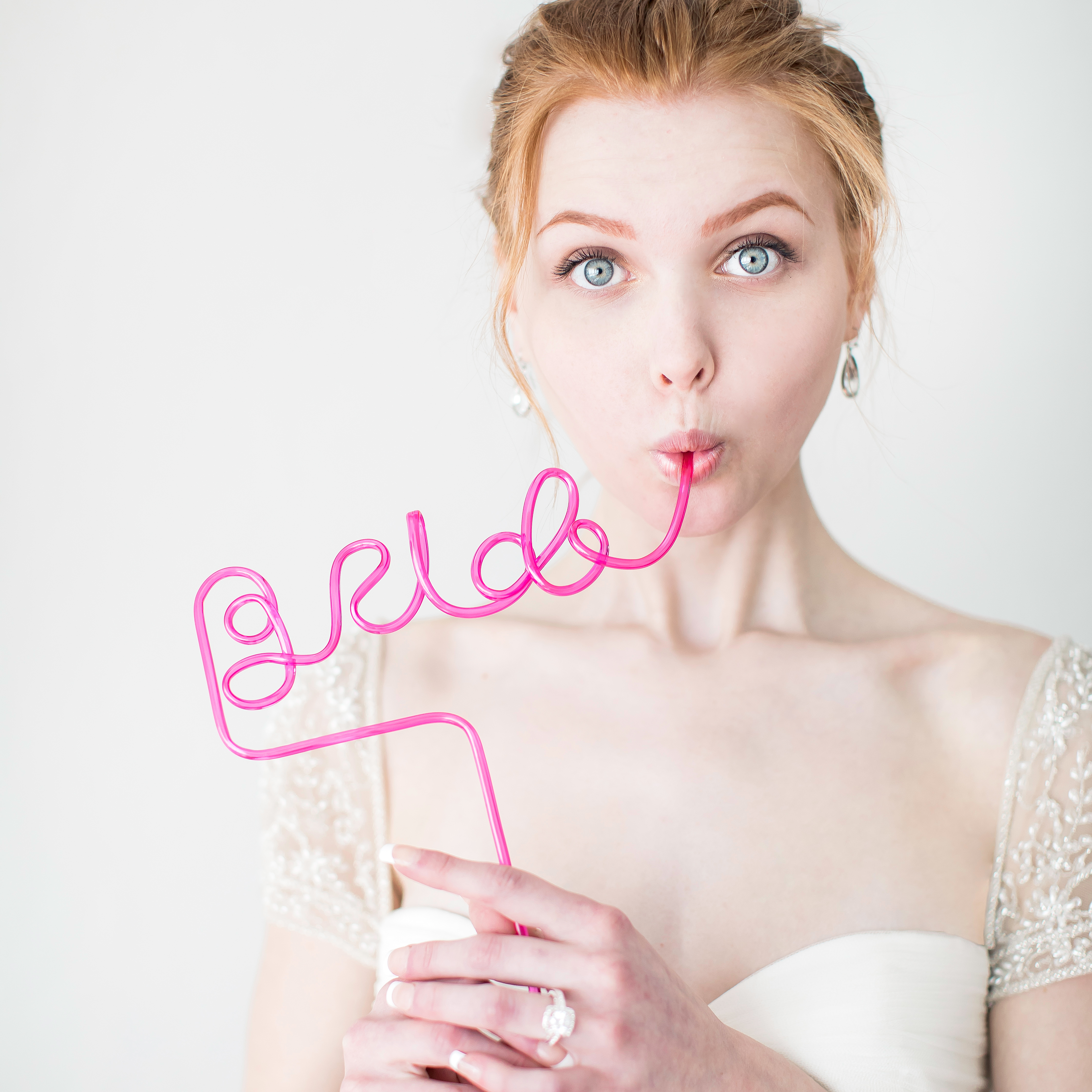 Bride drinking from pink straw that spells the word "bride"