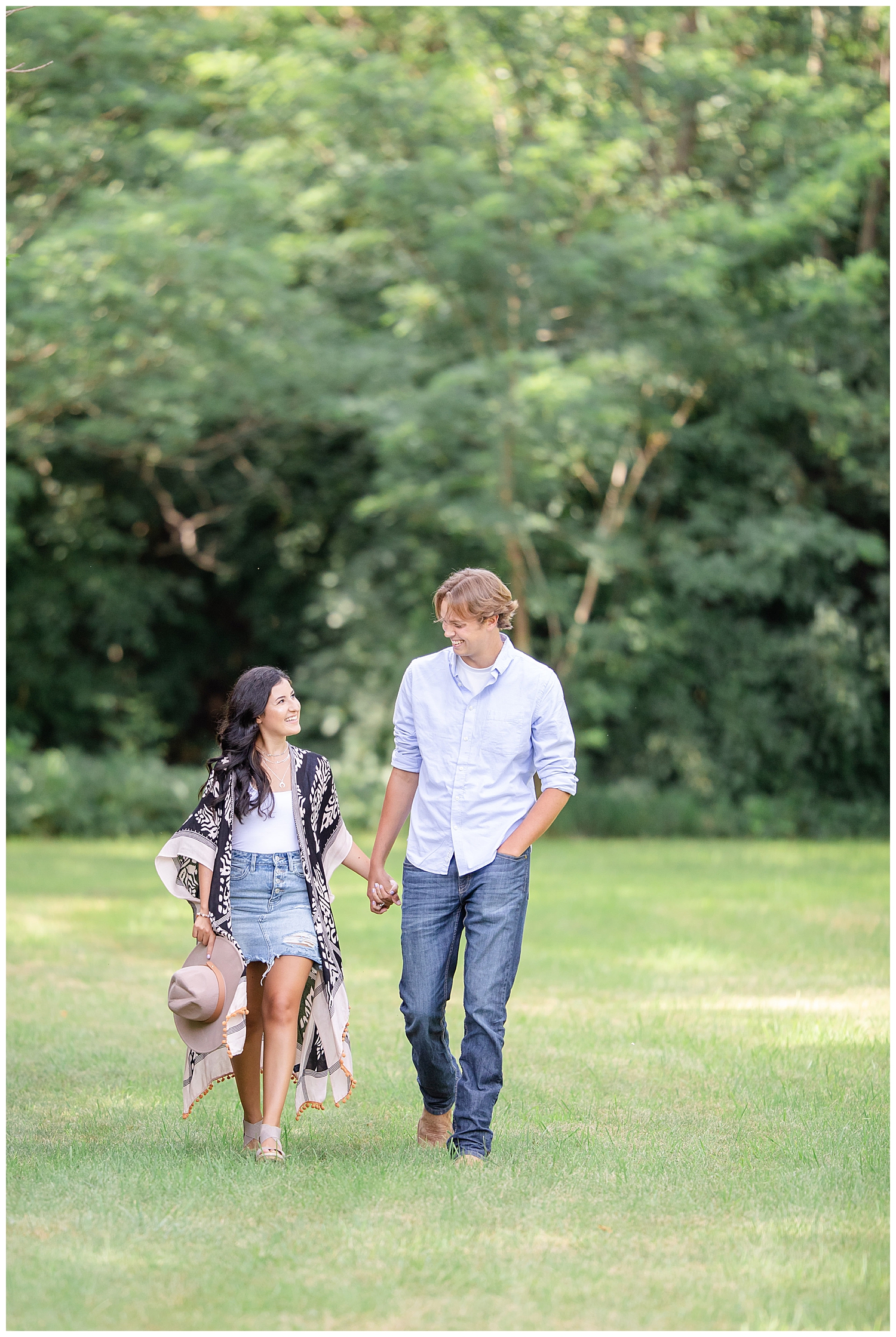 Couple walking and smiling at each other at Wall Lake, South Dakota during engagement session at sunset