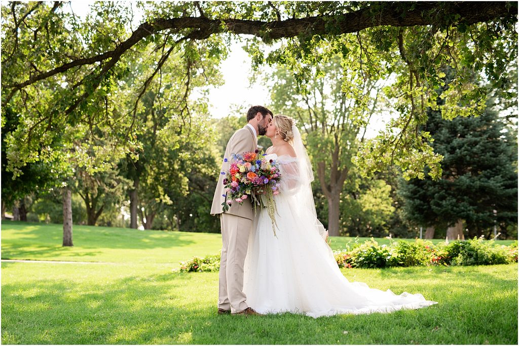 Bride and groom kissing happily at Tuthill Park in Sioux Falls, SD. Captured by Patty Solis Photography in Sioux Falls, South Dakota.